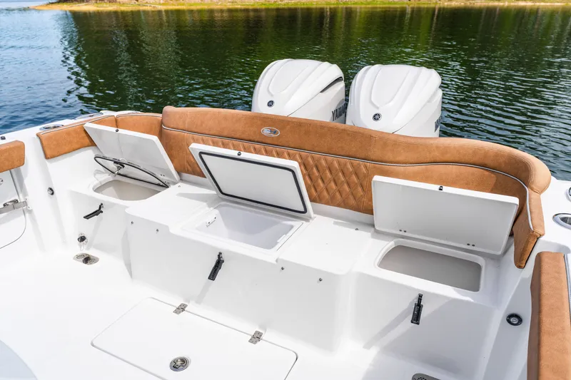 Slide: The Image of 2026 Sea Hunt Ultra 305SE boat with open storage compartments and dual engines on a calm lake. - 28