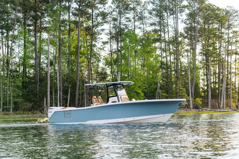 Slide: The Image of 2026 Sea Hunt Ultra 305SE boat cruising on a serene lake with forest backdrop. - 16
