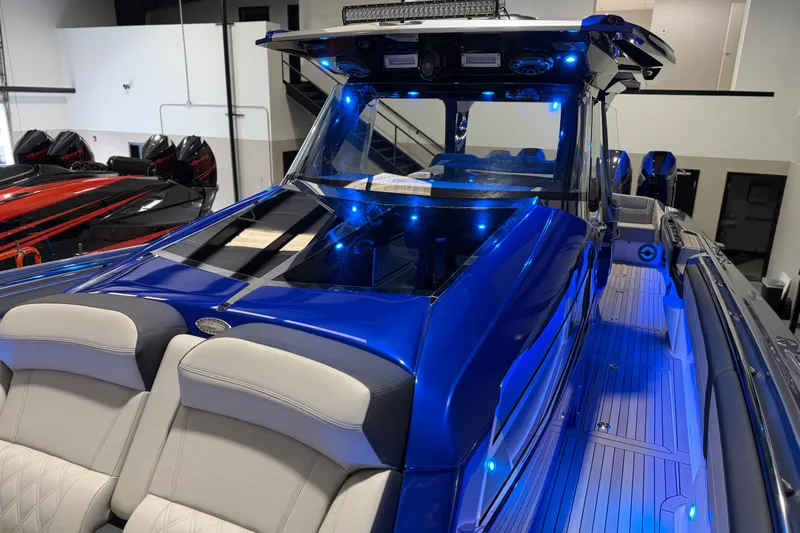 Slide: The Image of 2027 Nor-Tech 450 Sport boat with blue LED lighting and sleek design in a showroom. - 25