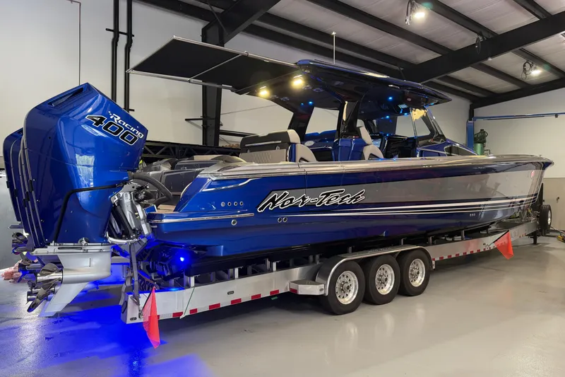 Slide: The Image of 2027 Nor-Tech 450 Sport boat with blue exterior and triple outboard engines on a trailer. - 58