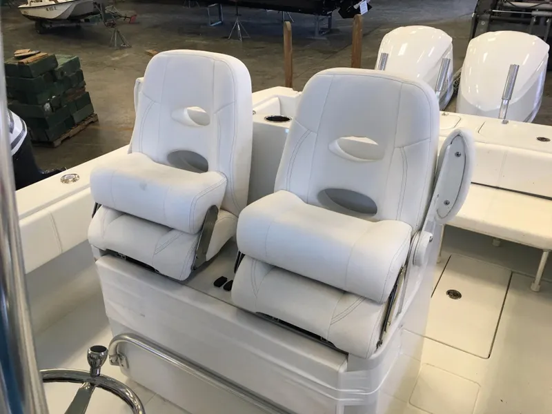 Slide: The Image of Two white, cushioned boat seats on a 2017 Contender 32 ST in a warehouse setting. - 25