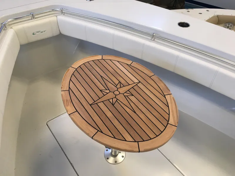 Slide: The Image of A sleek wooden table with a compass design sits in a white boat with cushioned seating. - 29