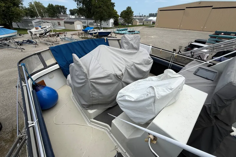 Slide: The Image of 1988 Carver 38 Aft Cabin Motor Yacht deck with covered equipment and marina background. - 13