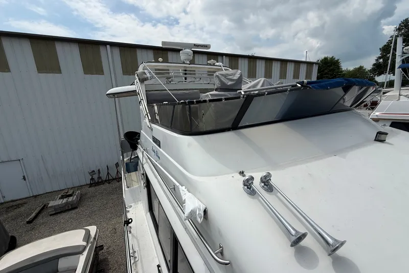 Slide: The Image of 1988 Carver 38 Aft Cabin Motor Yacht docked near a warehouse under cloudy skies. - 11