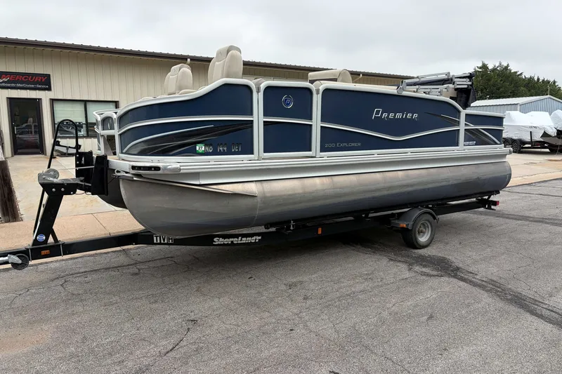 Slide: The Image of 2017 Premier 200 Explorer pontoon boat on trailer, parked outside a service center. - 2