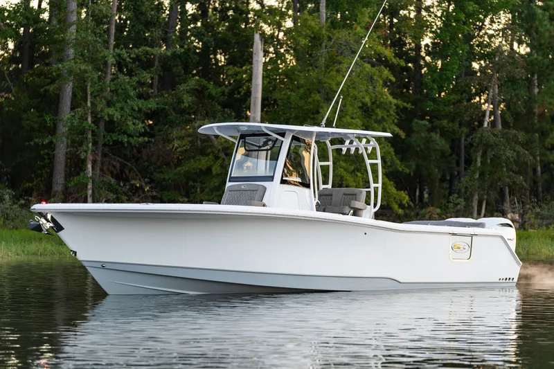 Slide: The Image of 2027 Sea Hunt Ultra 305SL boat on calm water, surrounded by lush greenery. - 14
