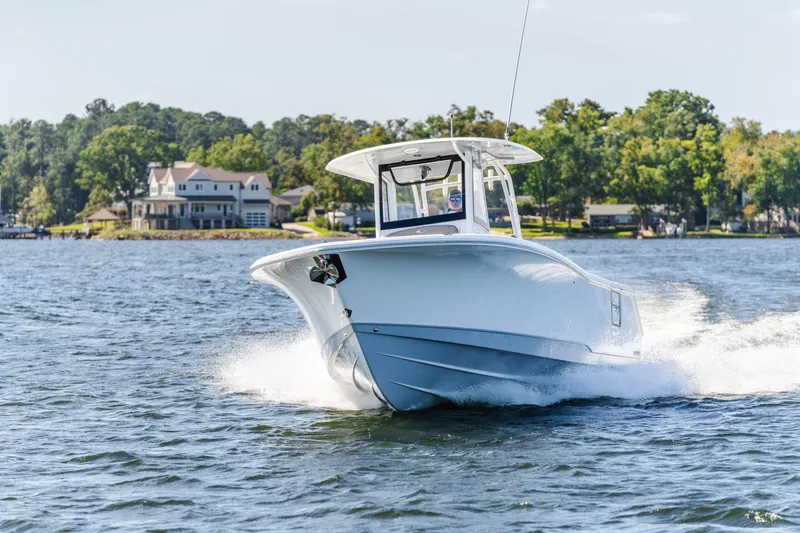 Slide: The Image of 2027 Sea Hunt Ultra 305SL cruising on a scenic lake with waterfront homes. - 33