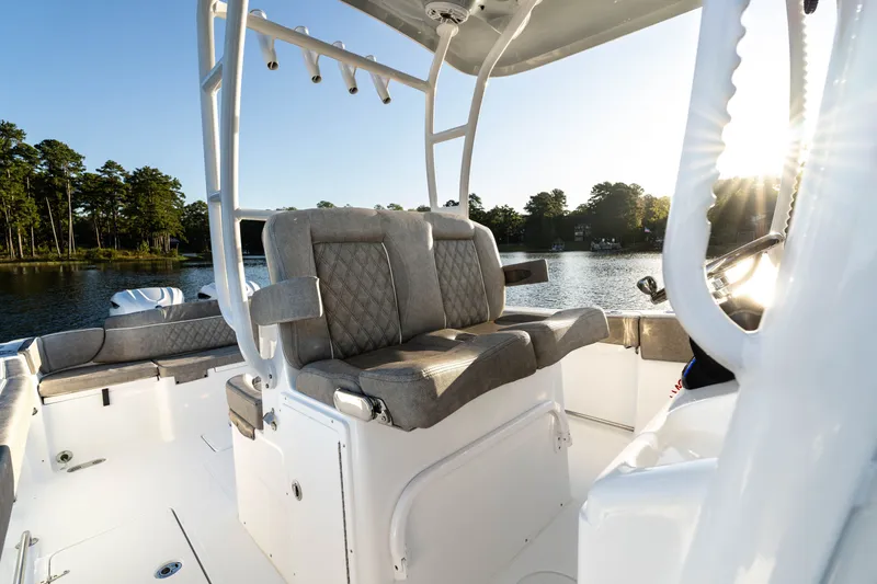 Slide: The Image of 2027 Sea Hunt Ultra 305SL boat interior with cushioned seating, on a serene lake. - 30