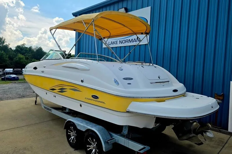 Slide: The Image of 2005 Chaparral Sunesta 254 boat with yellow accents on a trailer, parked by a blue building. - 34
