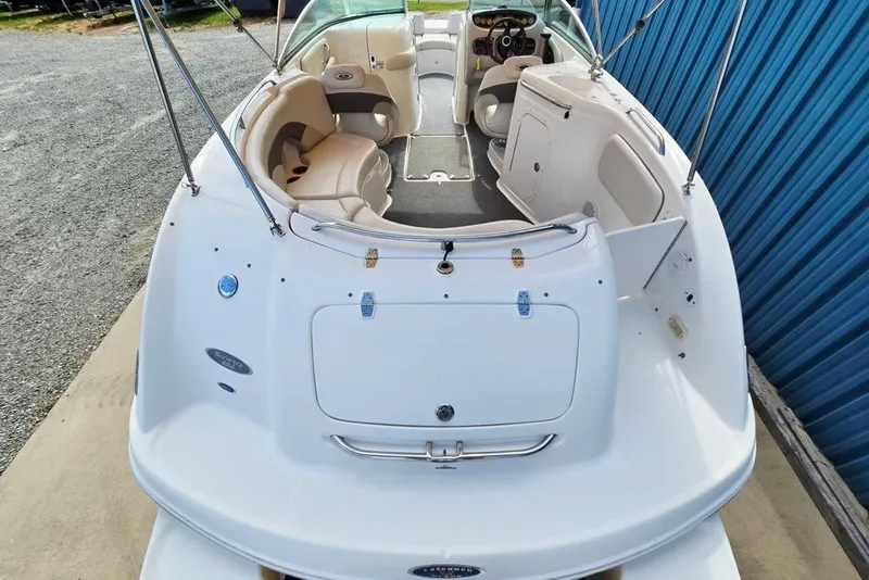 Slide: The Image of 2005 Chaparral Sunesta 254 boat interior with seating and steering wheel, docked near blue wall. - 16