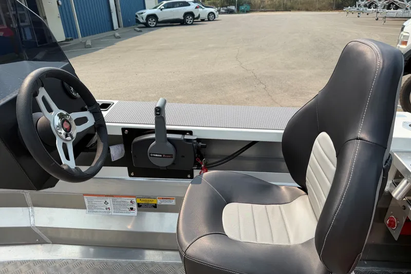 Slide: The Image of 2025 Stabicraft 1450 Explorer interior with steering wheel and seat in a parking lot. - 4
