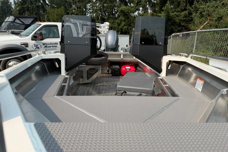 Slide: The Image of 2025 Stabicraft 1450 Explorer boat interior with seating and storage, parked near marine service truck. - 5