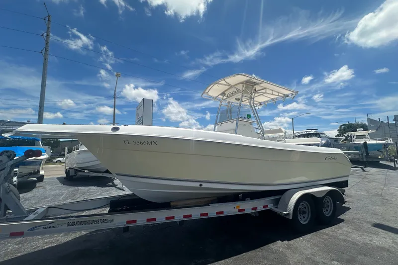 The Image of 2005 Cobia 254 Center Console boat on trailer under clear blue sky. - 0