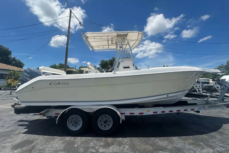 Slide: The Image of 2005 Cobia 254 Center Console boat on trailer under clear blue sky. - 7