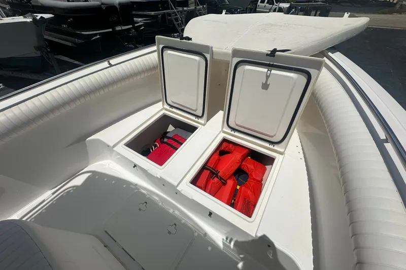 Slide: The Image of 2005 Cobia 254 Center Console boat with open storage compartments and life jackets. - 24