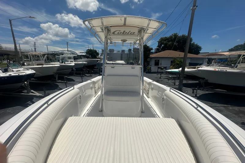Slide: The Image of 2005 Cobia 254 Center Console boat with white seating, docked under a sunny sky. - 25