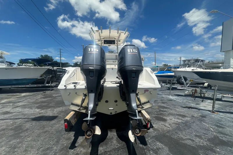 Slide: The Image of 2005 Cobia 254 Center Console boat with twin 115 horsepower engines, parked outdoors. - 4