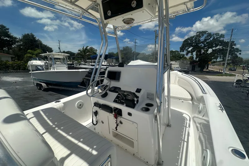 Slide: The Image of 2005 Cobia 254 Center Console boat with steering wheel and seating, under a clear blue sky. - 15