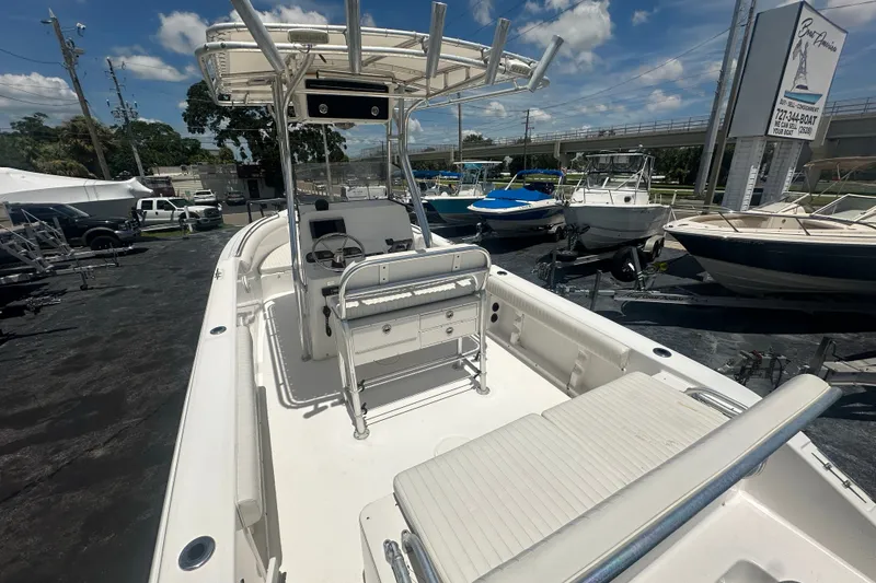 Slide: The Image of 2005 Cobia 254 Center Console boat with seating, parked in a marina under a clear sky. - 11