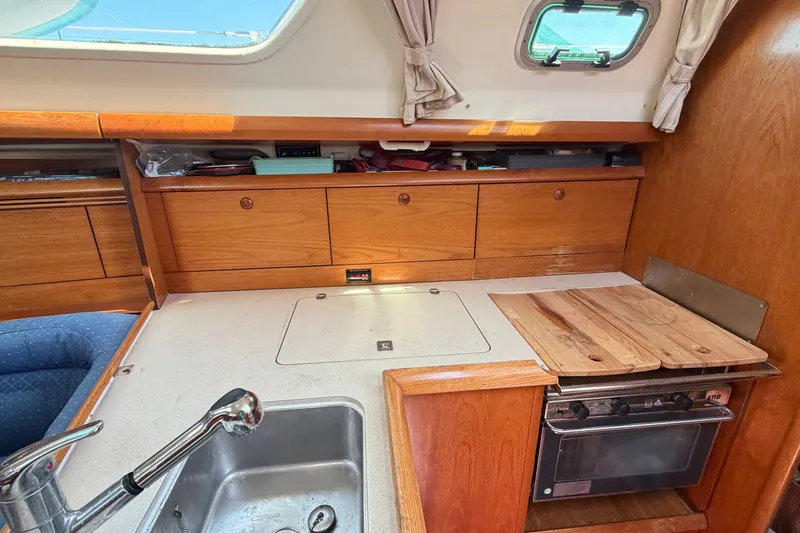 Slide: The Image of Interior of 2003 Jeanneau Sun Fast 37 yacht kitchen with wooden cabinetry and stove. - 24