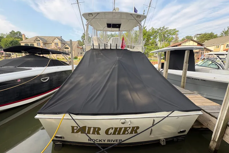 Slide: The Image of 2001 Blackfin 33 Flybridge boat docked, covered with a black tarp, in a marina setting. - 6