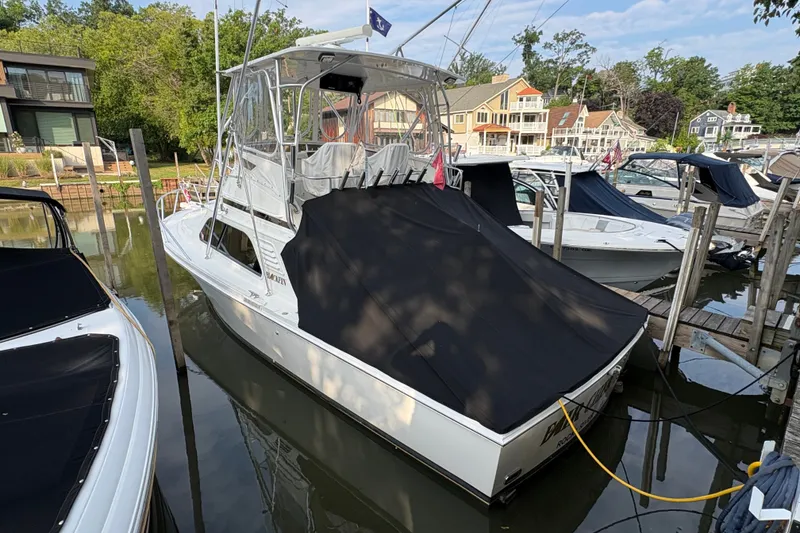 The Image of A 2001 Blackfin 33 Flybridge is docked, surrounded by other boats and houses. - 0