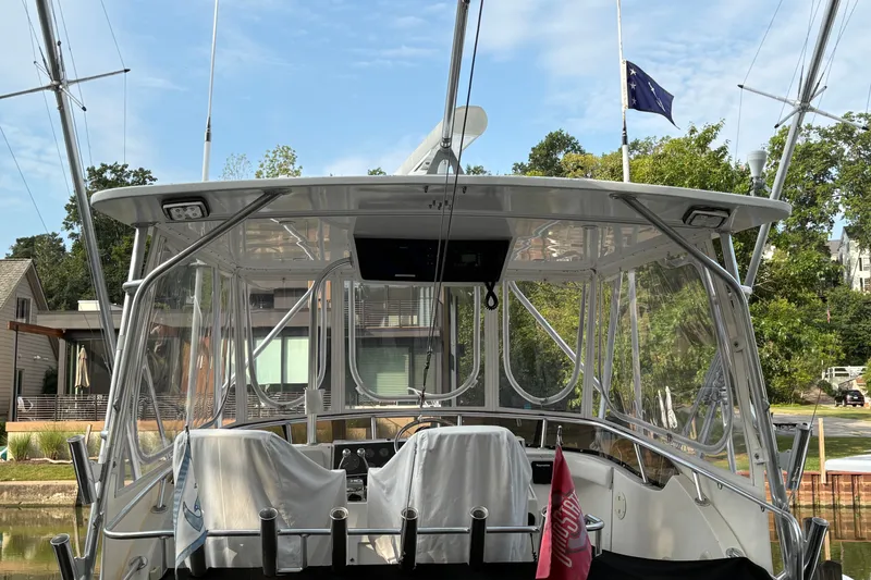 Slide: The Image of 2001 Blackfin 33 Flybridge boat docked, featuring covered seating and clear canopy. - 5