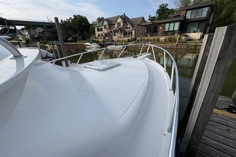Slide: The Image of 2001 Blackfin 33 Flybridge docked near waterfront homes, showcasing sleek design. - 4