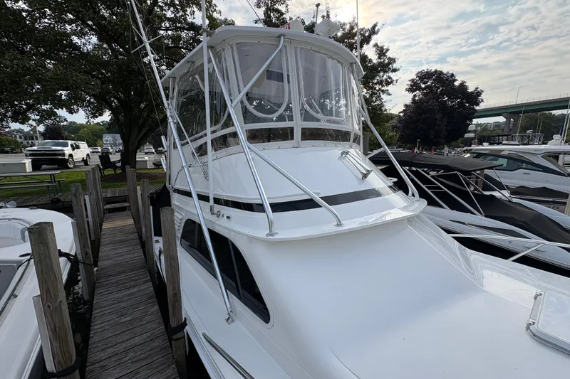 Slide: The Image of 2001 Blackfin 33 Flybridge boat docked at marina, featuring sleek design and flybridge enclosure. - 2