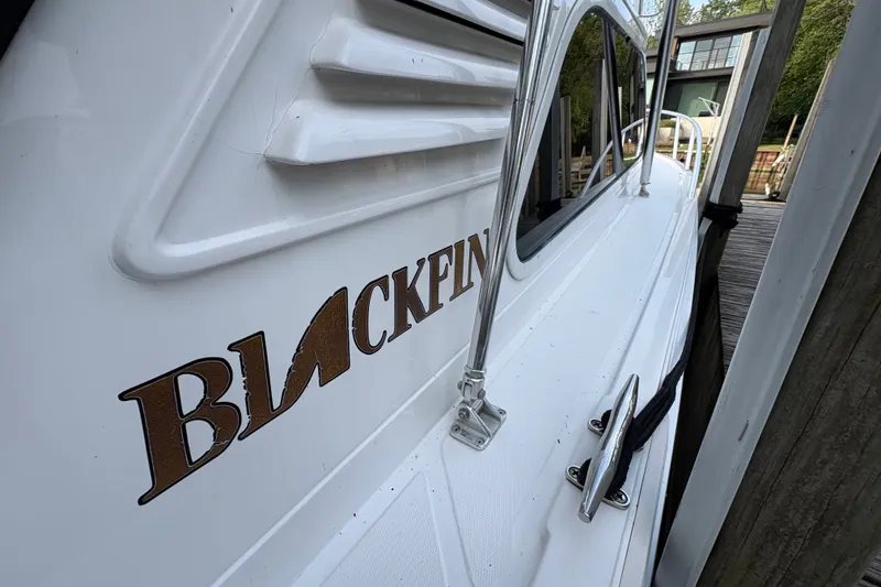 Slide: The Image of 2001 Blackfin 33 Flybridge boat docked, showcasing sleek design and branding. - 3