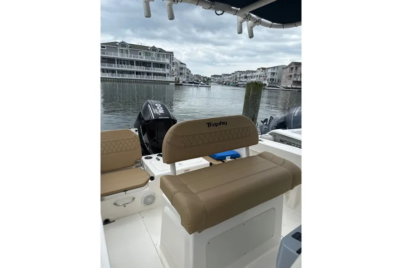 Slide: The Image of 2024 Trophy CC22 boat interior with tan seating, docked near waterfront homes. - 6