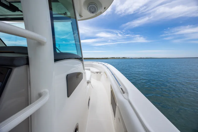 Slide: The Image of 2017 Boston Whaler 370 Outrage boat on calm water under a blue sky. - 37