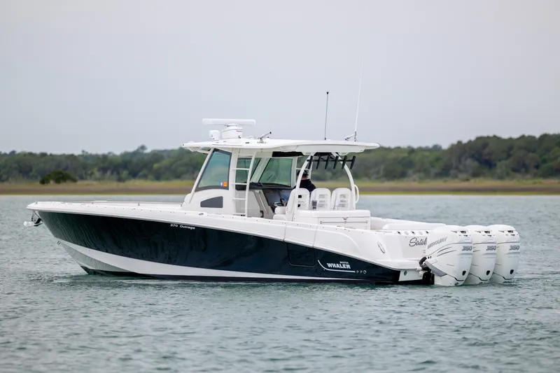 The Image of 2017 Boston Whaler 370 Outrage boat on calm water, featuring triple outboard engines. - 0