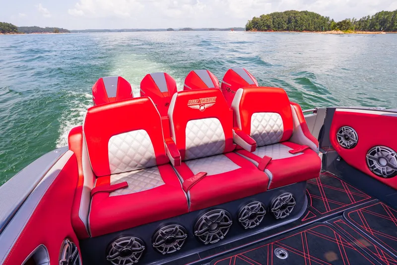 Slide: The Image of Red and white seating on 2022 Deep Impact 399 Sport boat, cruising on a scenic lake. - 70