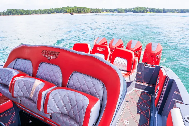 Slide: The Image of 2022 Deep Impact 399 Sport boat with red and gray seating, cruising on a scenic lake. - 58
