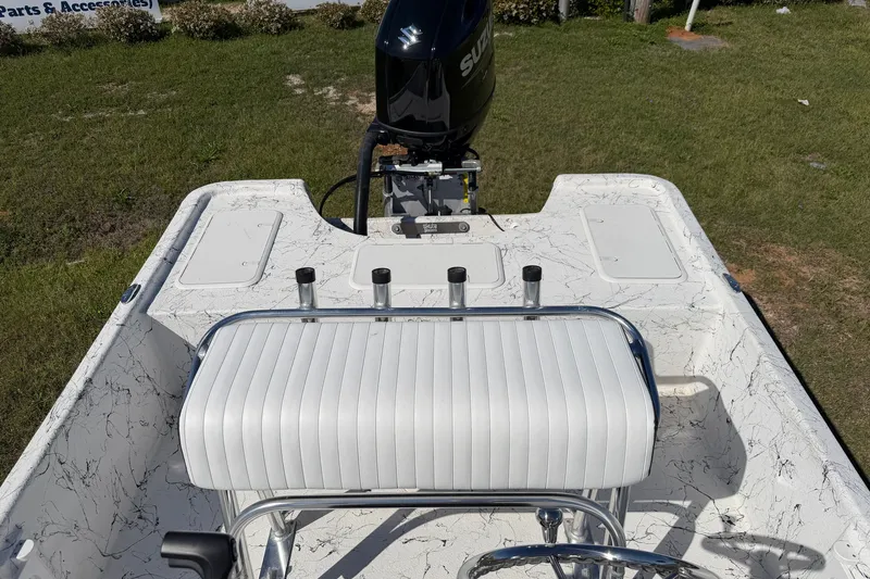 Slide: The Image of 2026 Skuta 21 Tournament V boat interior with white seating and motor, parked on grass. - 23