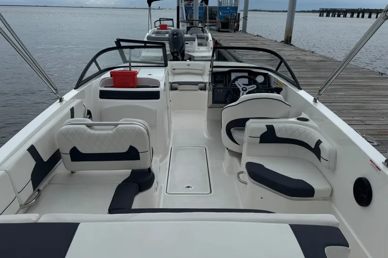 Slide: The Image of 2024 Bayliner VR6 Bowrider OB interior with seating, steering wheel, and dockside view. - 6
