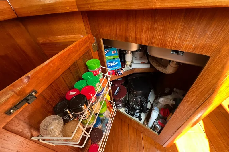 Slide: The Image of Wooden cabinet interior with spices, coffee maker, and storage in a 1990 Hunter Legend 35.5 yacht. - 20