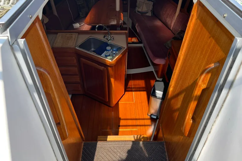Slide: The Image of Interior view of 1990 Hunter Legend 35.5 sailboat, featuring wooden cabinetry and compact kitchen area. - 15