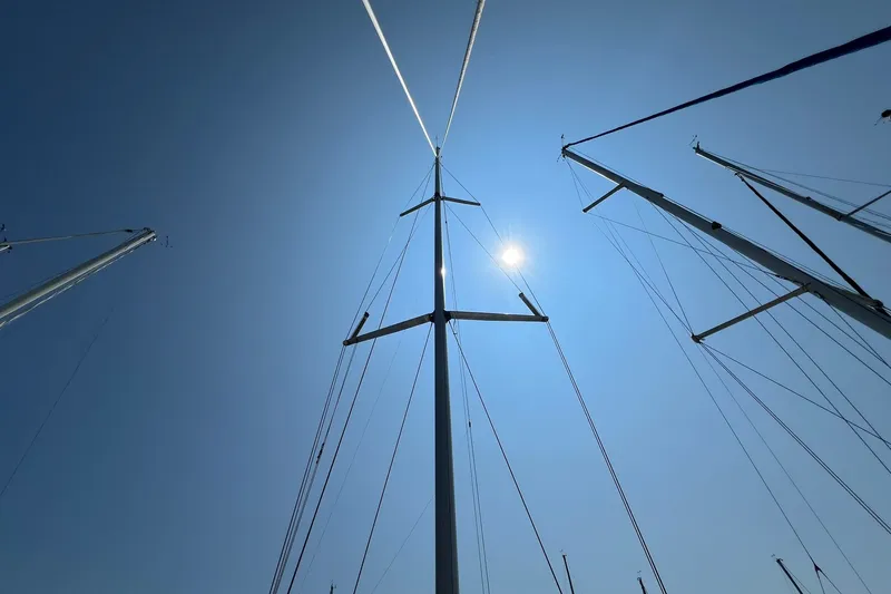 Slide: The Image of Sailboat masts against a clear blue sky, featuring a 1990 Hunter Legend 35.5. - 37