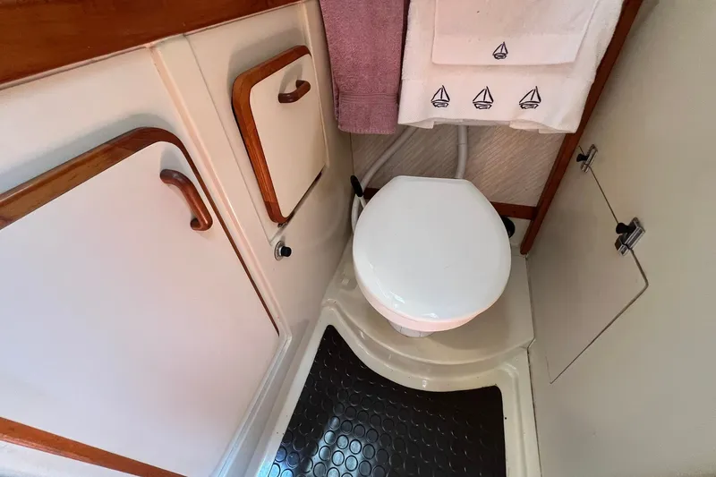 Slide: The Image of Compact bathroom in 1990 Hunter Legend 35.5 sailboat with wooden accents and nautical-themed towels. - 31