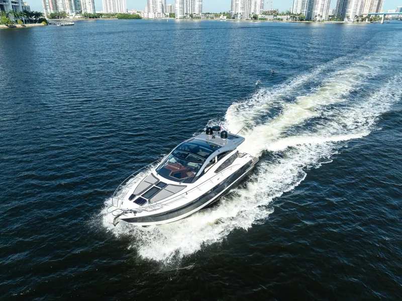 Slide: The Image of 2016 Galeon 430 HTC yacht cruising on open water with city skyline in background. - 8