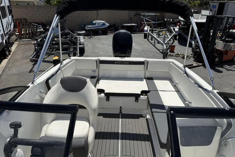 Slide: The Image of 2023 Bayliner VR4 Bowrider I/O boat interior with seating and steering wheel, parked outdoors. - 14