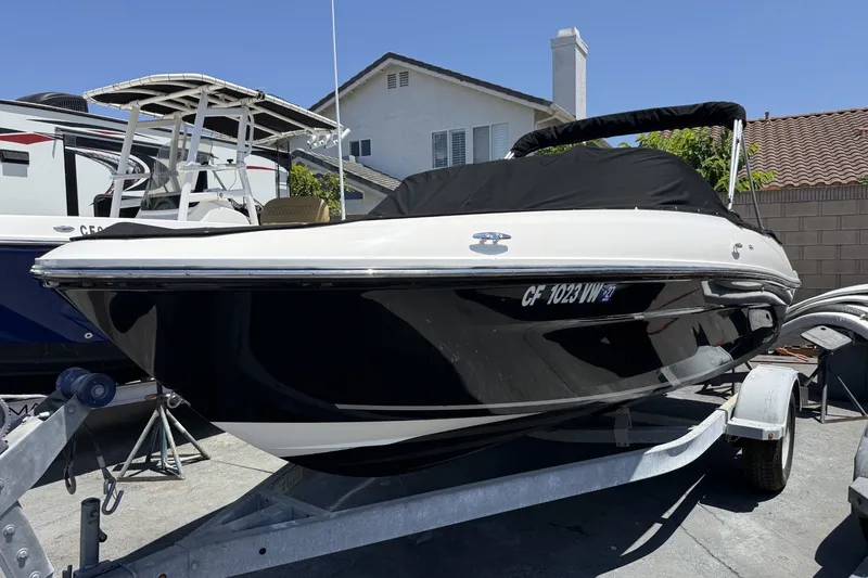 Slide: The Image of 2023 Bayliner VR4 Bowrider I/O on trailer, black hull, covered, parked outdoors. - 2