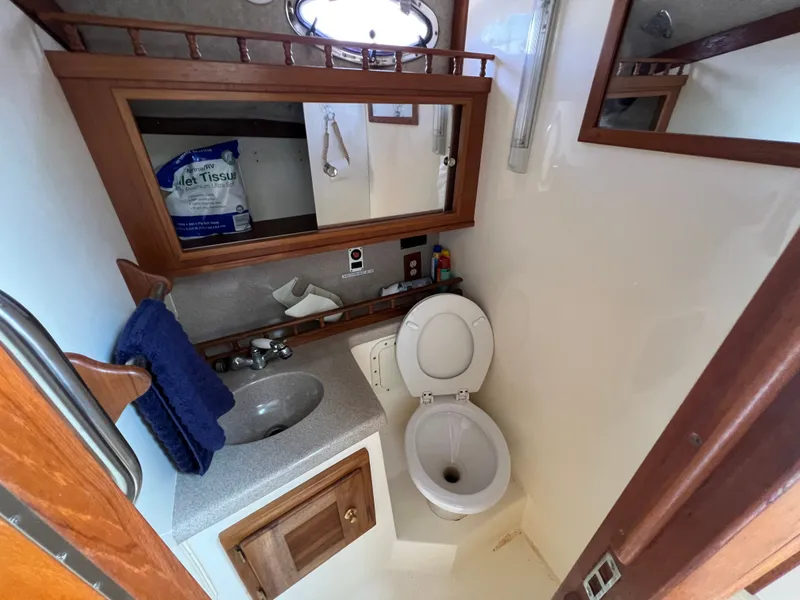 Slide: The Image of The image shows the bathroom of a 2002 Albemarle 280 Express Fisherman. It features a toilet, sink, and mirror. - 16
