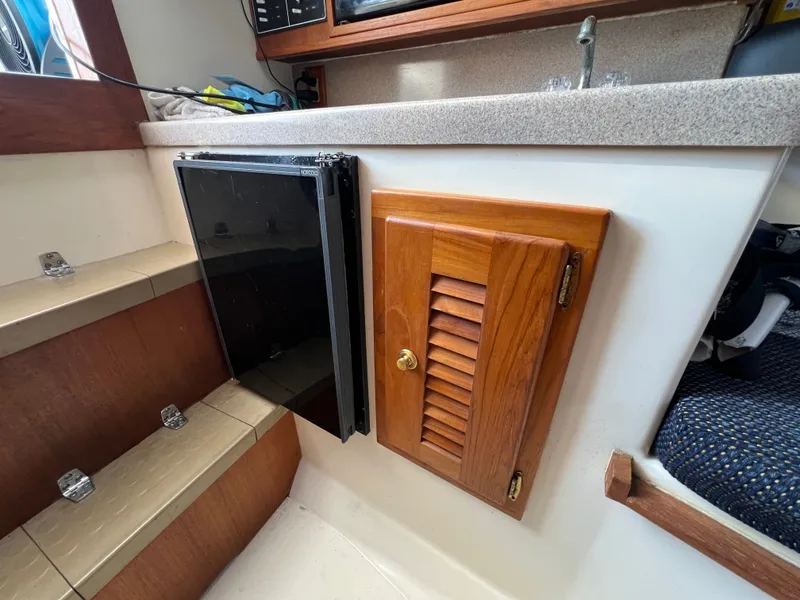 Slide: The Image of Boat interior with a wooden cabinet and fridge next to a staircase. - 15