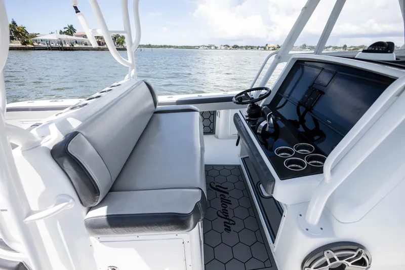 Slide: The Image of 2015 Yellowfin 39 Offshore boat interior with helm, seating, and cup holders on a sunny day. - 21