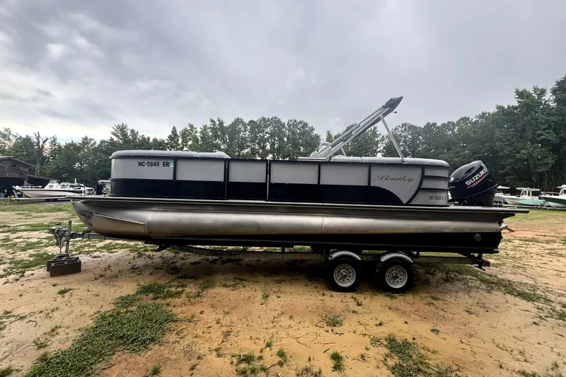Slide: The Image of 2021 Bentley Pontoons 243 Navigator on trailer, parked outdoors under cloudy sky. - 19