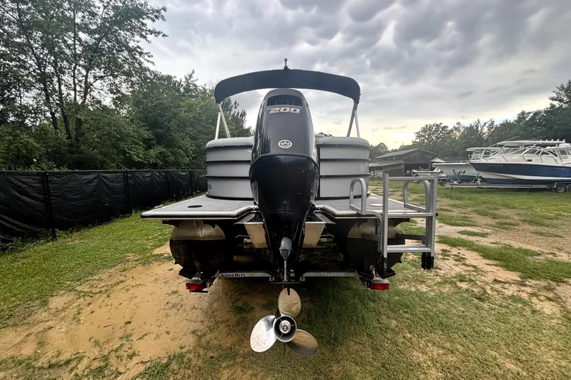 Slide: The Image of 2021 Bentley Pontoons 243 Navigator with outboard motor, parked on grassy area under cloudy sky. - 16