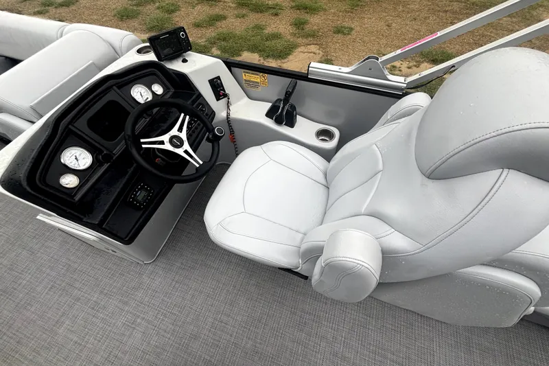 Slide: The Image of 2021 Bentley Pontoons 243 Navigator helm with steering wheel and gauges, featuring plush seating. - 10